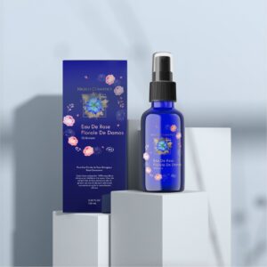 Organic rosewater spray bottle with floral motifs set beside its can on a geometric stand and light blue background.
